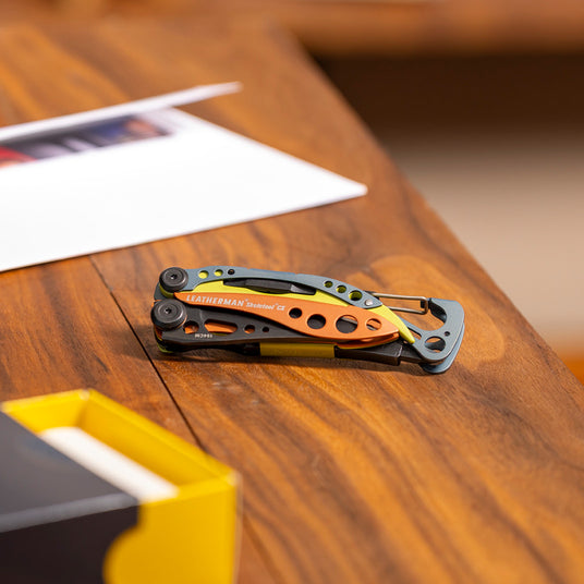 Translation missing: en.Colorful Leatherman Skeletool CX multi-tool resting on a wooden desk