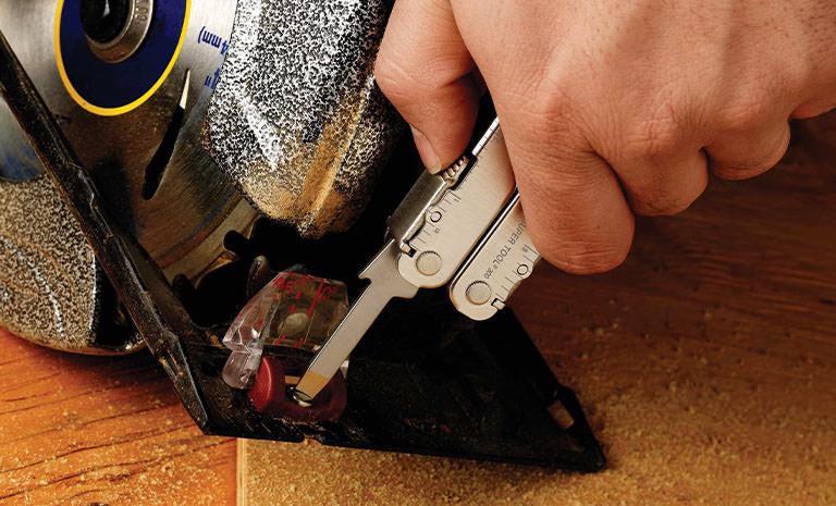 Translation missing: en.Man using Leatherman Super Tool 300 to tighten screw on saw machine