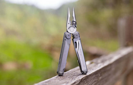 Translation missing: en.Stainless Steel Leatherman Wave® Plus multi-tool on a wooden fence in nature