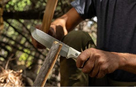 Translation missing: en.A person using an Alpine Leatherman Pioneer™ knife to split a wood plank in half, showcasing the functionality of our knives collection