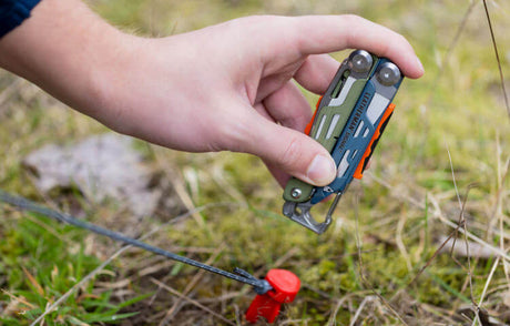 Translation missing: en.Someone using a Tundrascape Leatherman Signal® to hammer a tent stake for camping