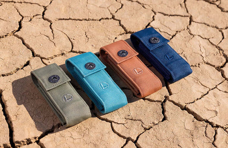 Translation missing: en.Four Leatherman nylon sheaths in Tundra, Turquoise, Sienna, and Midnight colors on cracked earth