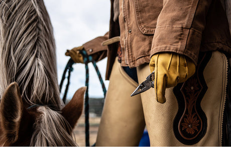 Translation missing: en.Person in ranch workwear and gloves holding a Leatherman multi-tool beside a horse, representing durable tools for the agriculture industry