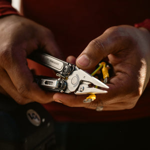 Translation missing: en.Person cutting rope with a Black DLC stainless steel Leatherman ARC® in a grassy outdoor setting