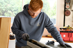 Translation missing: en.A person wearing a storm blue Leatherman Classic Hoodie working in a bright workshop