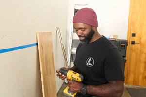 Translation missing: en.A person wearing a black Leatherman Classic Tee holding a yellow power drill while working indoors