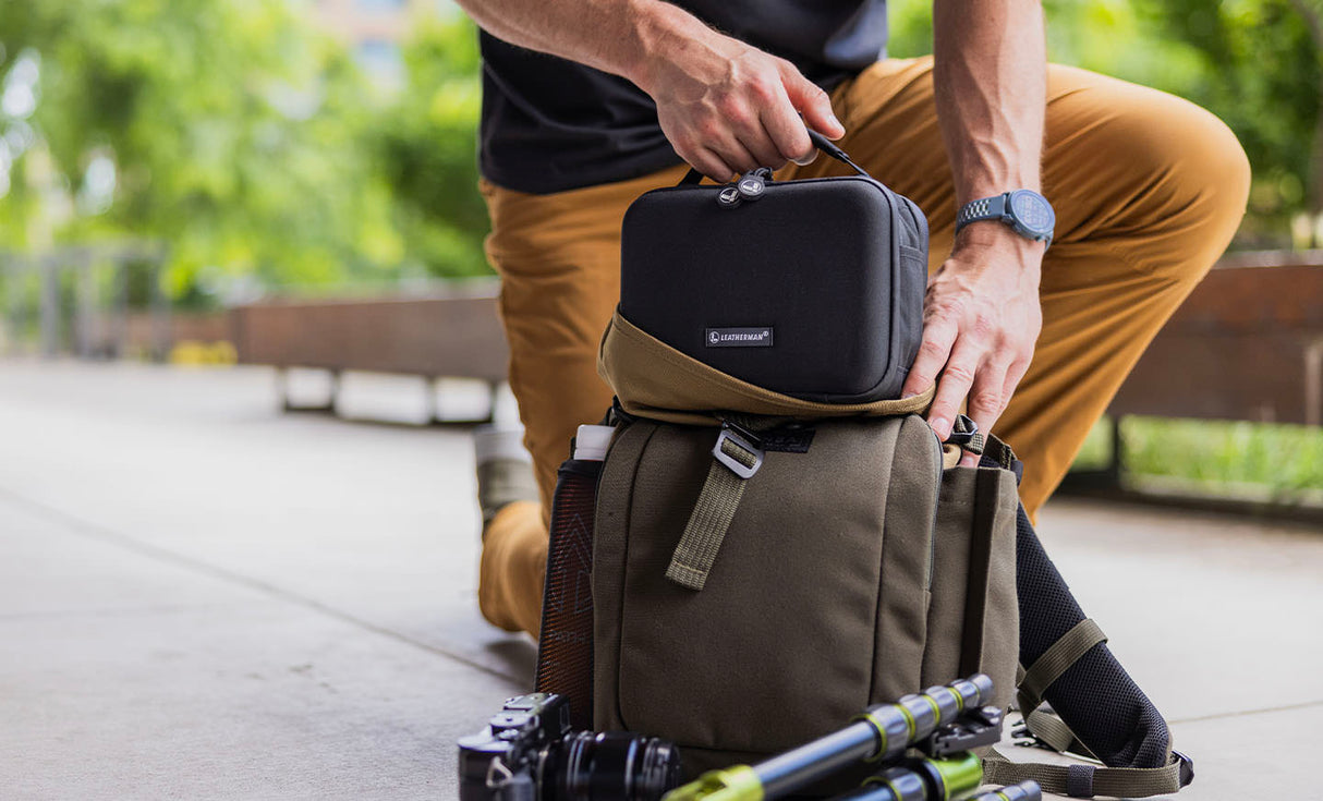 Translation missing: en.Man placing Leatherman® Adapt Kit in crossbody bag