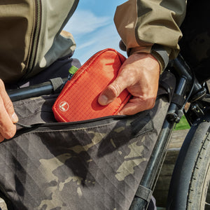 Translation missing: en.Hand placing an Aurora Leatherman tool pouch into a zippered bike frame bag