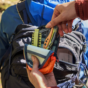 Translation missing: en.Hands holding an Aurora Leatherman Tool Pouch with multitools and bits beside an open hiking backpack