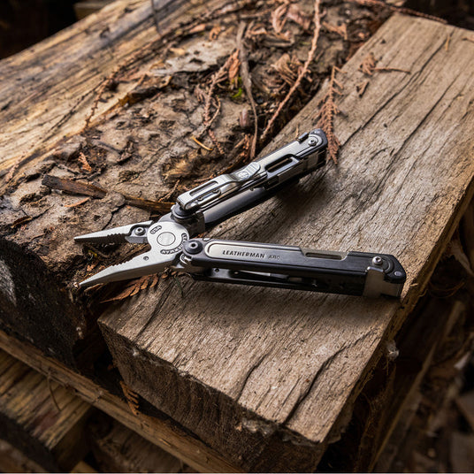 Translation missing: en.Leatherman ARC multi-tool with pliers extended resting on weathered wood outdoors, representing durable and versatile tools for agriculture and ranch work