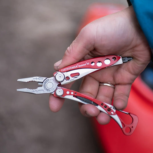 Translation missing: en.Hand holding a red Leatherman Skeletool RX rescue multi-tool with pliers extended