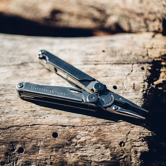 Translation missing: en.Open Leatherman Wave+ multi-tool resting on weathered wood outdoors