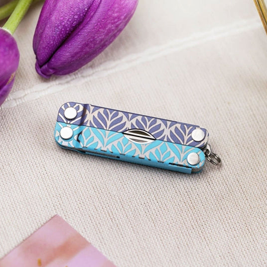 Translation missing: en.Decorative patterned Leatherman Micra multi-tool placed beside purple flowers on a fabric surface