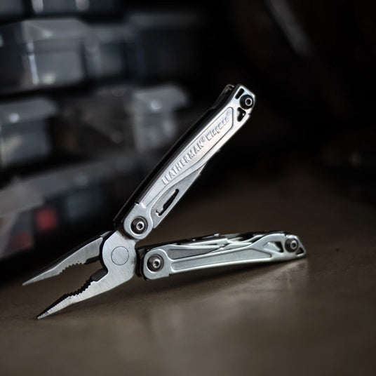 Translation missing: en.Open Leatherman Wingman multi-tool with spring-action pliers displayed on a dark tabletop