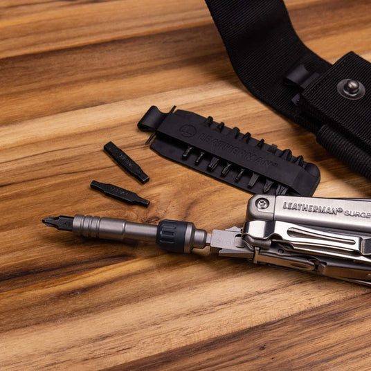 Translation missing: en.Leatherman ratchet driver accessory with interchangeable bits attached to a Surge multi-tool on a wooden workbench