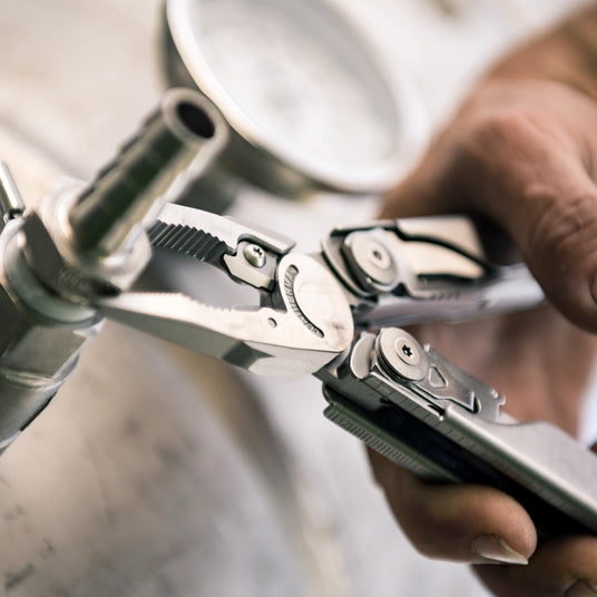 Translation missing: en.Leatherman Surge multi-tool pliers gripping plumbing hardware during a repair task