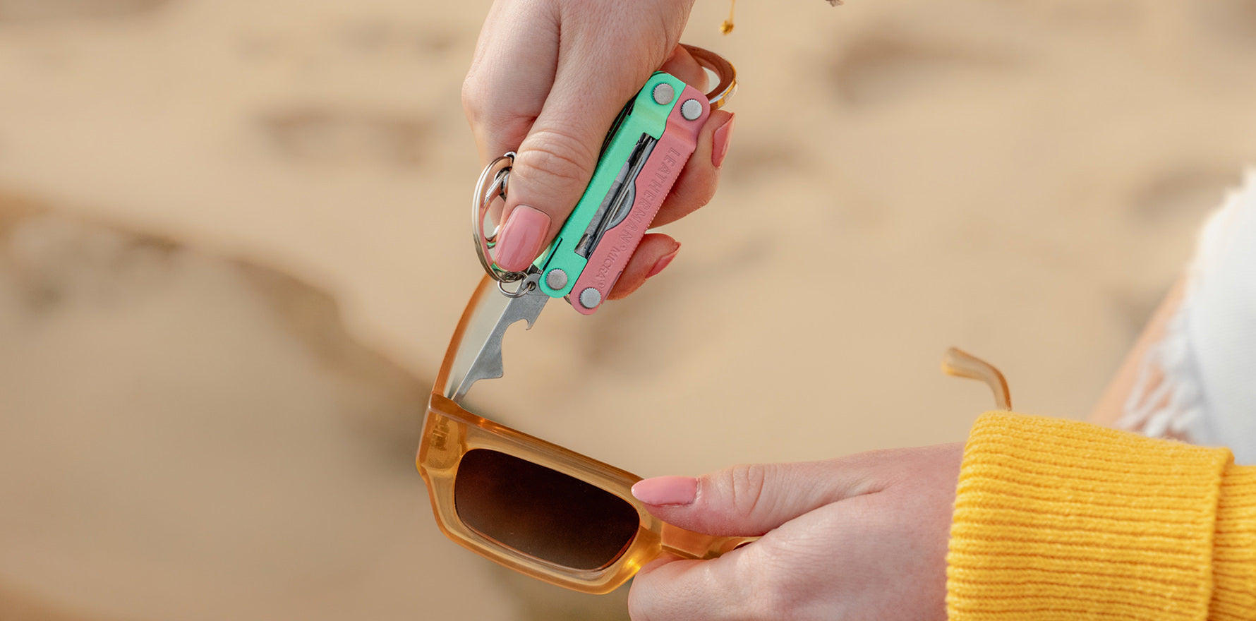 Person using the extra small screwdriver on a Leatherman Micra® in Bayside color to tighten sunglasses on the beach.