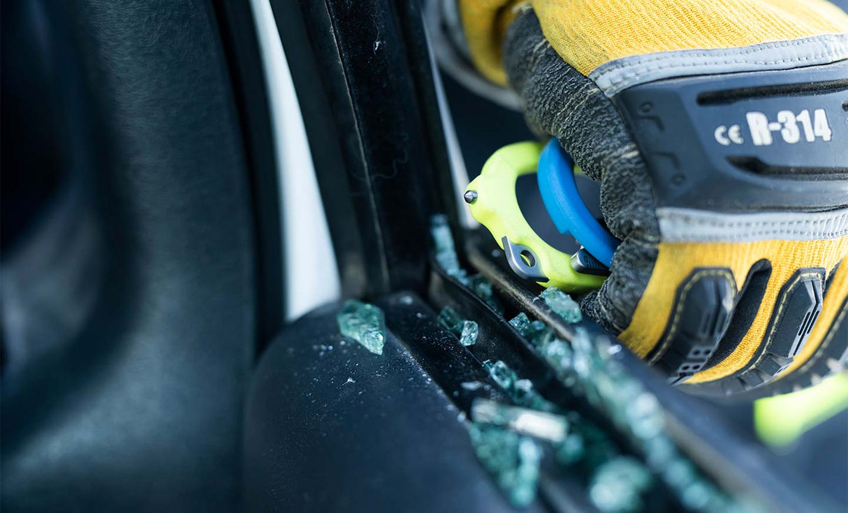 Translation missing: en.Person using yellow and blue Leatherman Raptor® Rescue glass breaker to break a car window