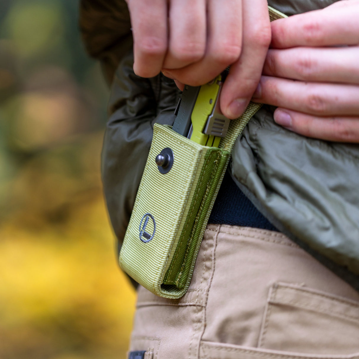 Translation missing: en.Person wearing a green jacket holstering a Mossy Slate Leatherman Rebar® in a matching sheath on their hip