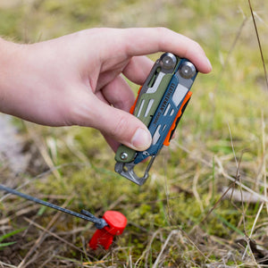 Translation missing: en.A person using the hammer on a Tundrascape Leatherman Signal® to hammer a tent stake in a patch of grass