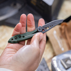 Translation missing: en.Hand holding an OD green Leatherman Skeletool KB folding knife with open blade