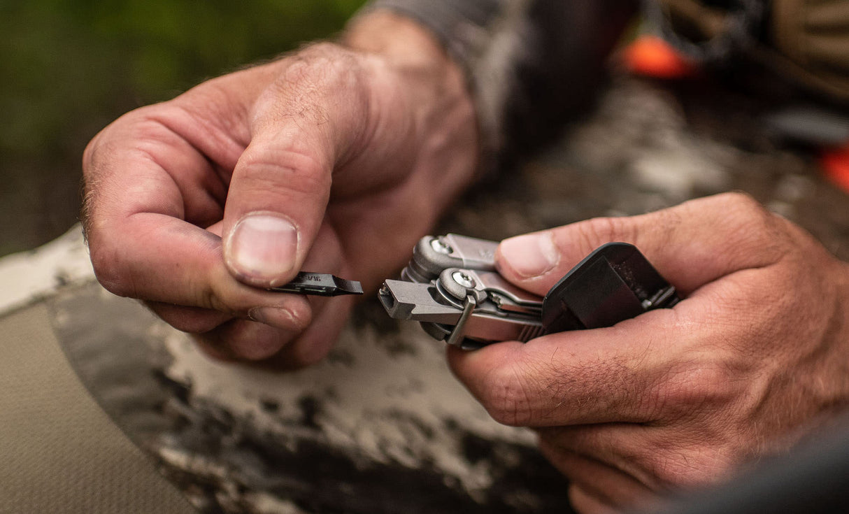 Translation missing: en.Hands inserting a bit into a Stainless Steel Leatherman Wave® Plus multitool outdoors